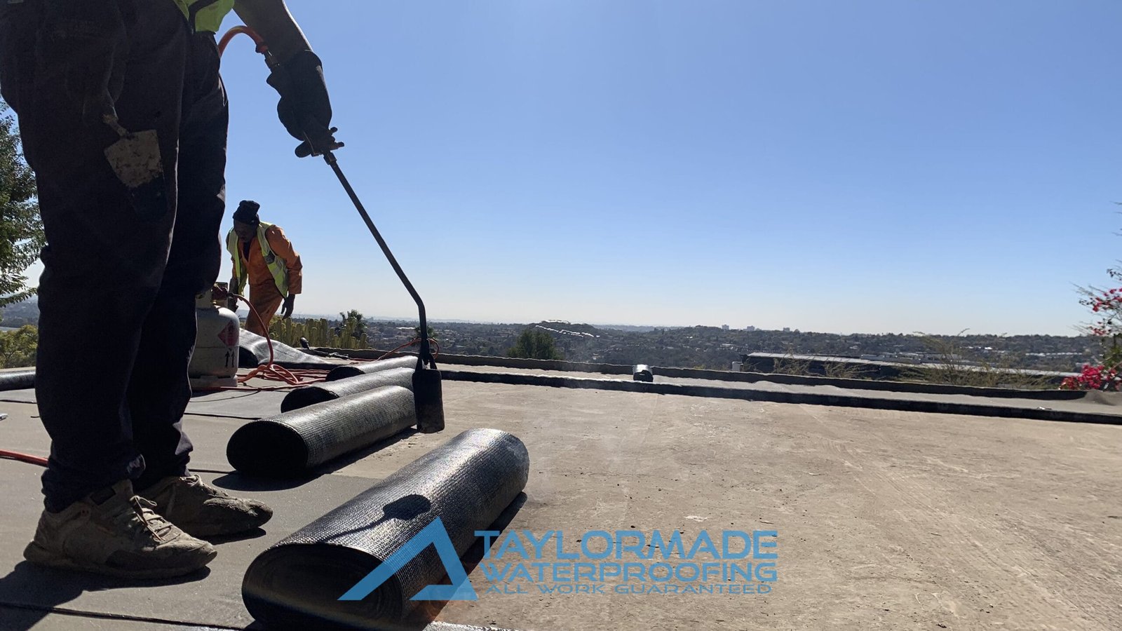 Close up view of TM Waterproofing using blow torch to install a torch‑on waterproofing membrane.