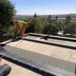TM Waterproofing on flat roof installing torch‑on waterproofing membrane.