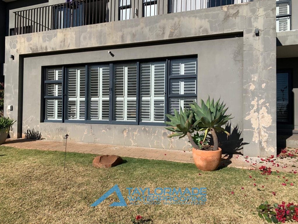 Exterior wall with visible cracks and surface deterioration before waterproofing repair.