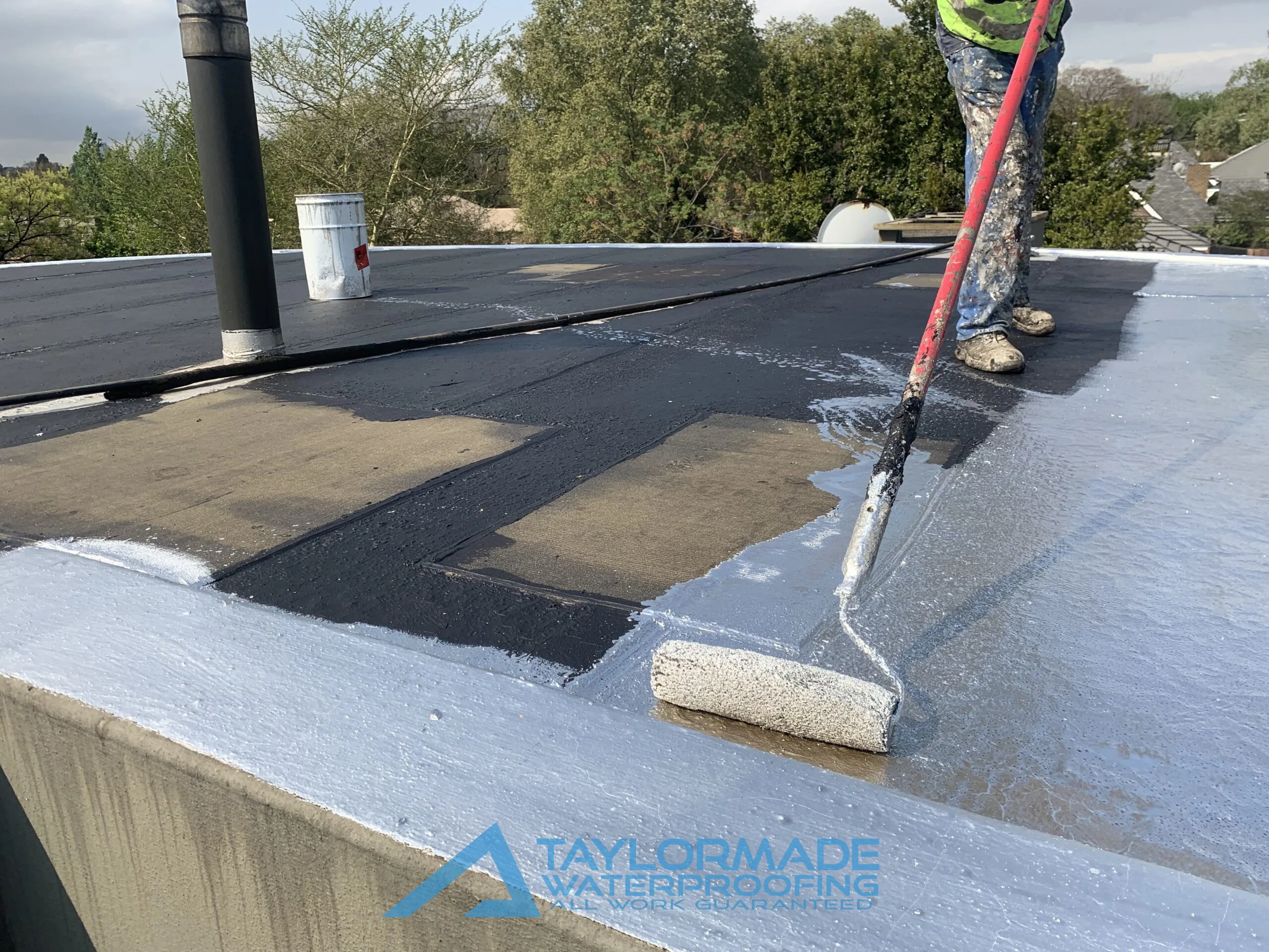 TM Waterproofing painting the flat roof surface at the Parktown North waterproofing project, ensuring even coverage and lasting protection.