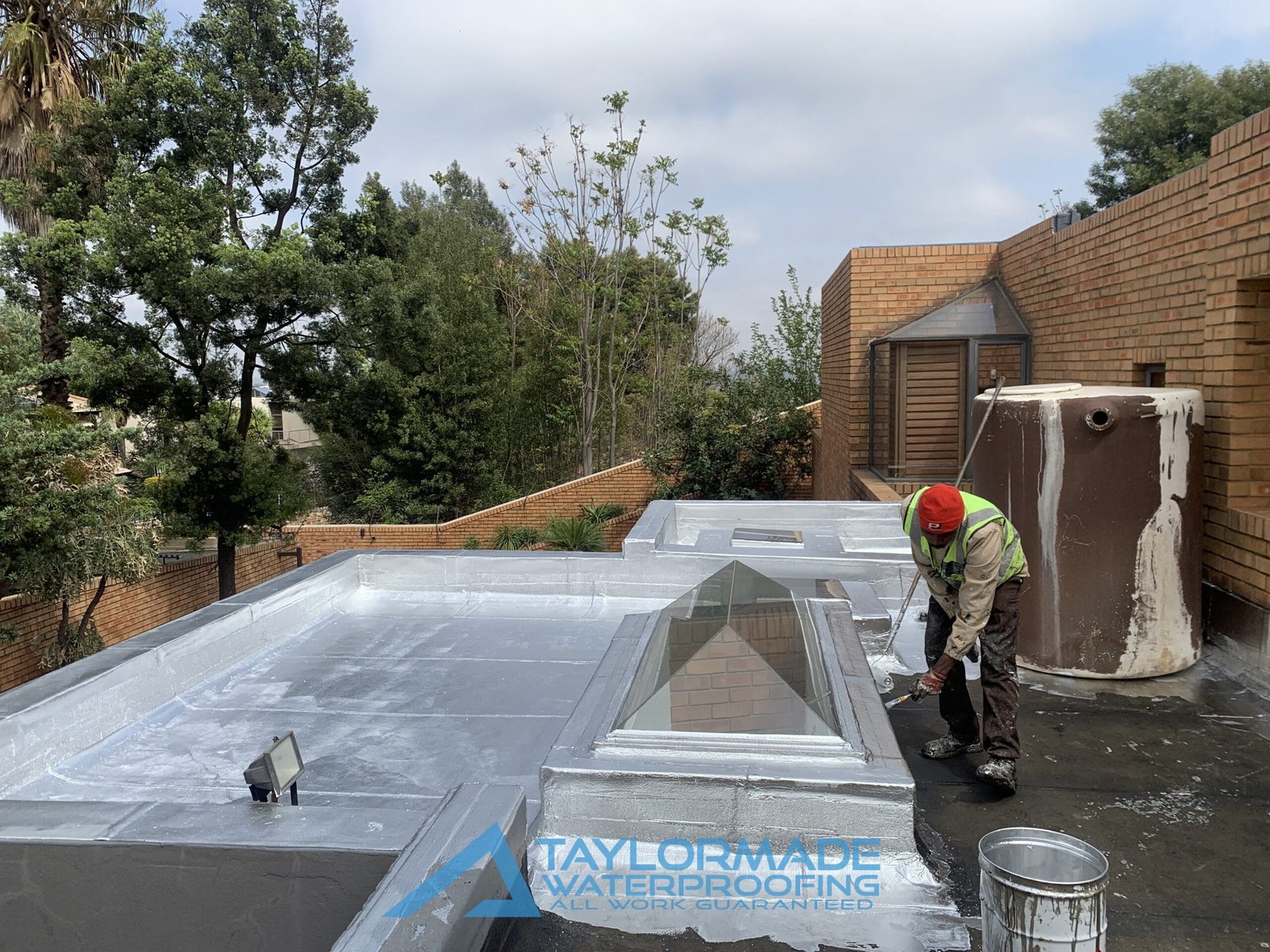 TM Waterproofing painting a flat roof after torch-on membranes application, before completion.