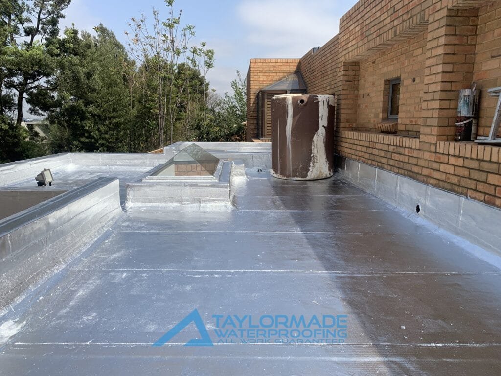 Flat roof with silver paint & torch-on membranes application completed, demonstrating full board & torch waterproofing coverage.