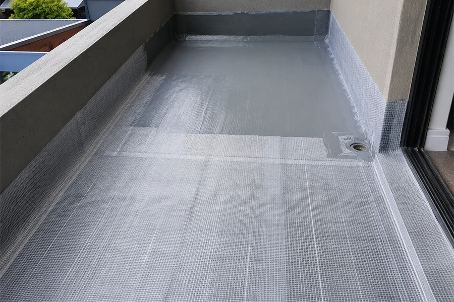 Balcony drainage waterproofing image showing Polyfelt reinforced membrane system applied around balcony floor, wall junctions and outlet
