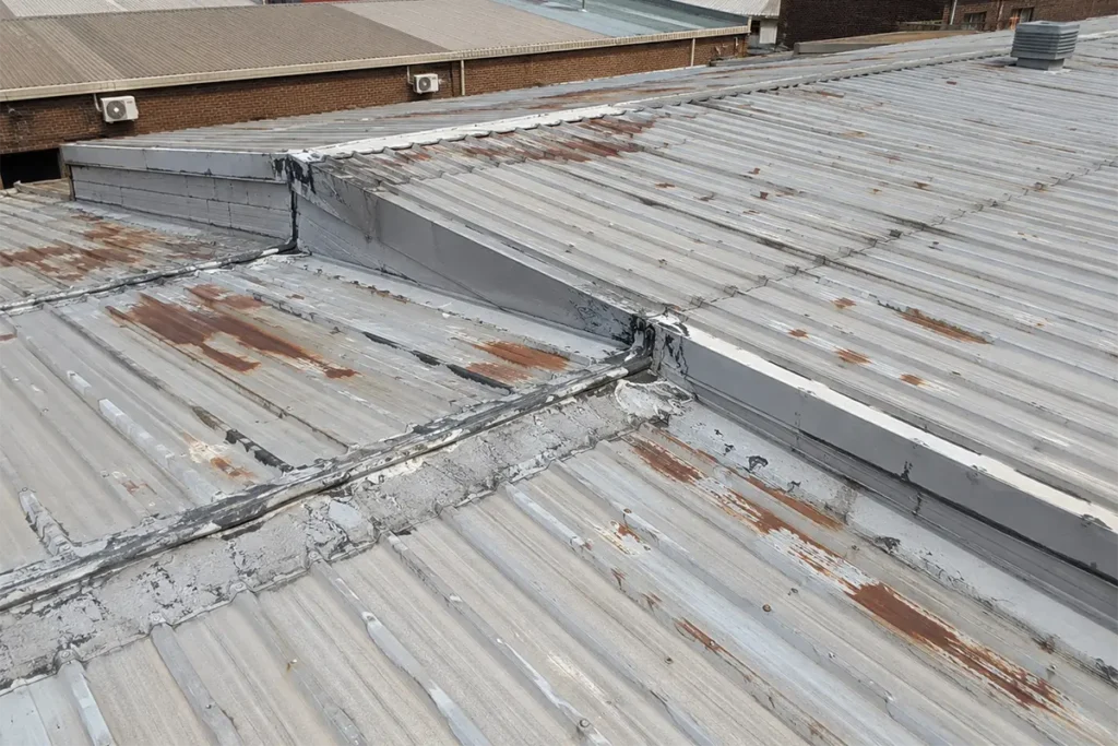 Metal roof waterproofing Johannesburg problem showing commercial corrugated roof with rust, overlaps and failing waterproofing details