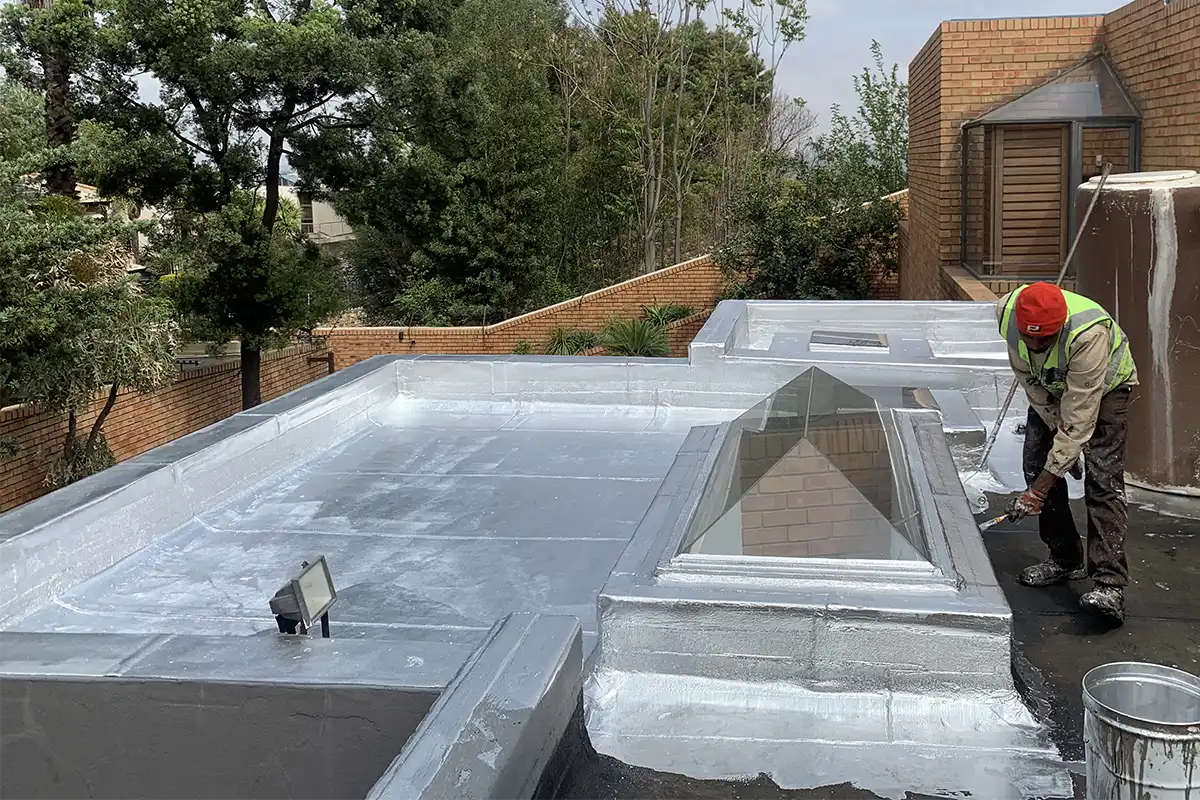 Roof Waterproofing Bedfordview UV coating being applied beside skylight after torch-on
