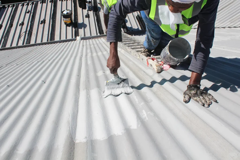 Roof waterproofing Westcliff worker applying protective coating over reinforced fabric on a pitched metal roof
