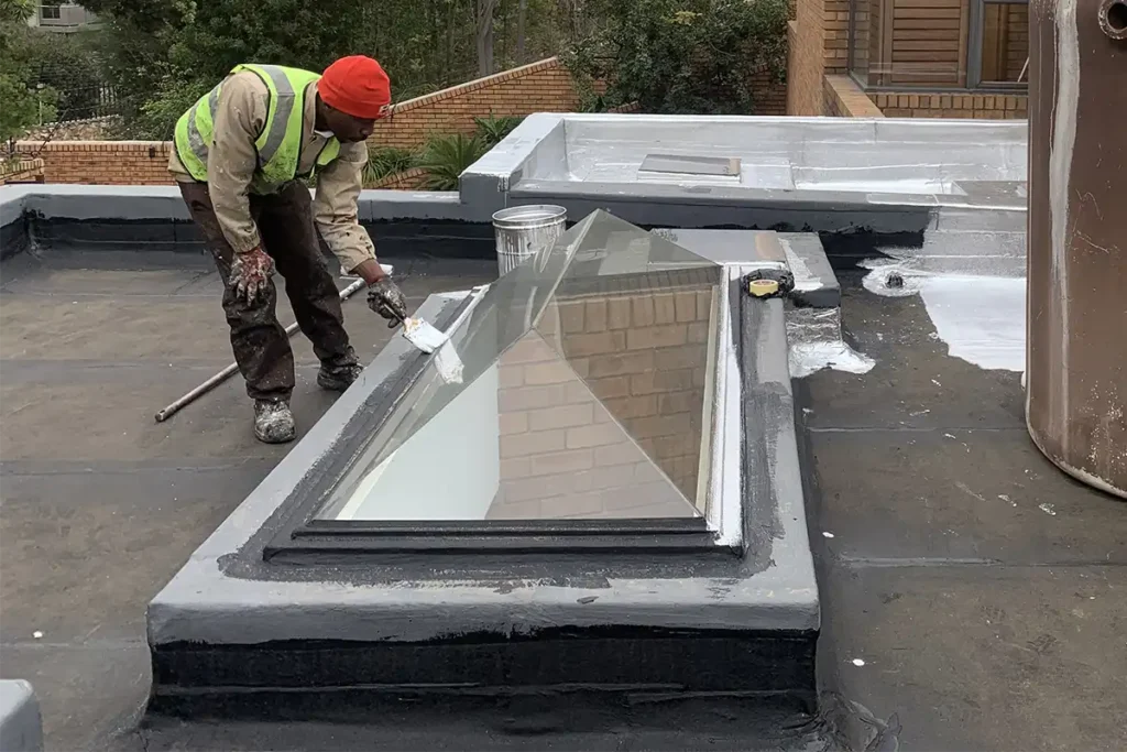 bedfordview-uv-paint-application.webp Torch-on waterproofing Bedfordview worker applying UV protective paint after membrane installation