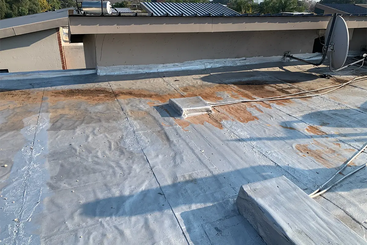 Flat roof waterproofing Randburg before work showing failed waterproofing and stained roof surface