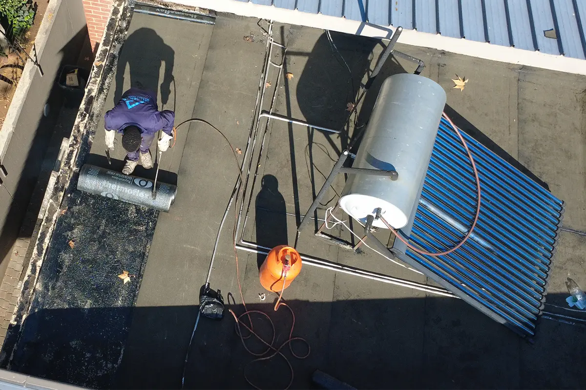Torch-on waterproofing Blackheath with worker rolling membrane across flat roof section