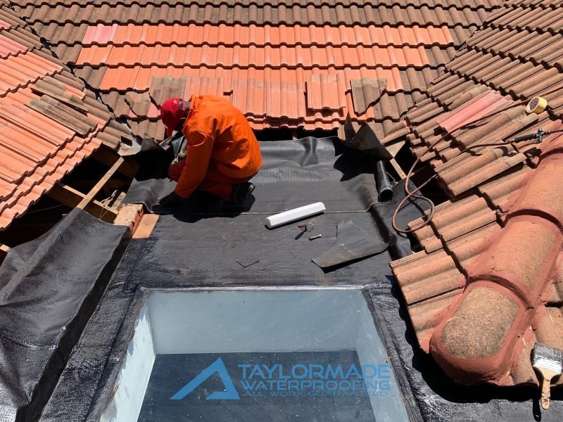 TM Waterproofing applying torch‑on waterproofing membrane on a roof surface while tiles are being replaced.