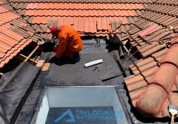 TM Waterproofing applying torch‑on waterproofing membrane on a roof surface while tiles are being replaced.