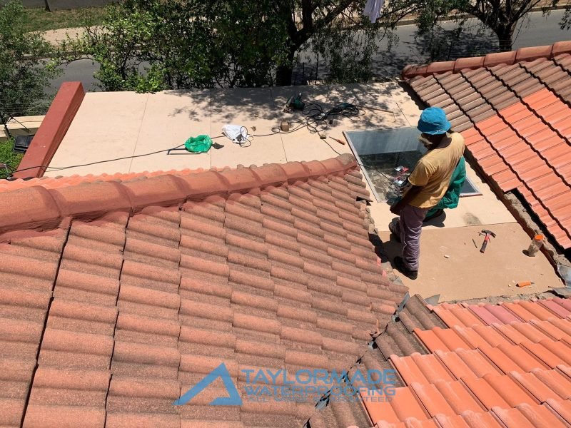 Roof of a house with workers installing roof tiles as part of the restoration process.