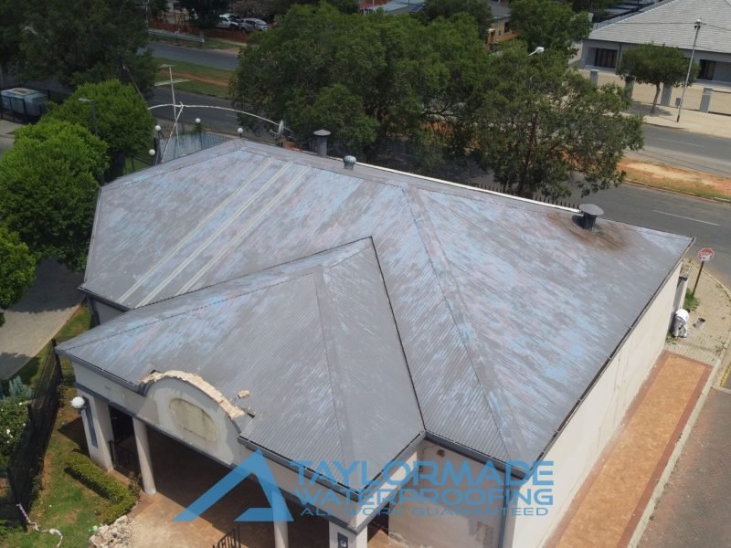 Drone right front view of a corrugated roof section with protective paint applied, showing completed waterproofing work.