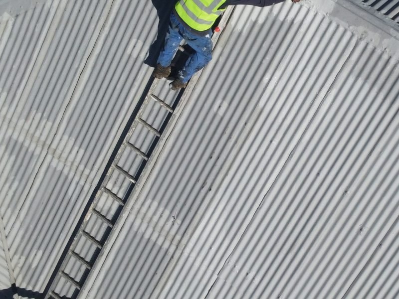 TM Waterproofing repairing and painting a corrugated roof section for long lasting protection.
