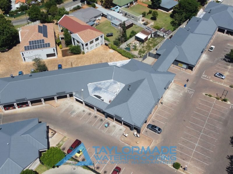 Wide aerial view of corrugated roof with membranes installed and protective paint applied, showing complete roof coverage.