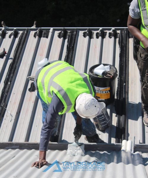 TM Waterproofing applying a protective coating on a corrugated roof for long lasting durability and weather protection.