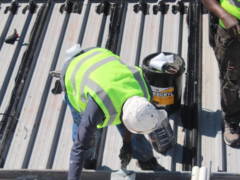 TM Waterproofing applying a protective coating on a corrugated roof for long lasting durability and weather protection.