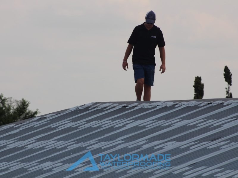 Corrugated roof under inspection and painting drying, showing ongoing quality control and roof protection.