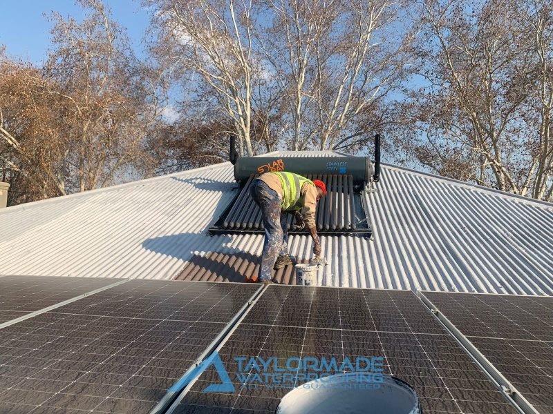 TM Waterproofing applying gray protective coating to the Parkhurst roof, part of flat roof waterproofing for water damage protection.