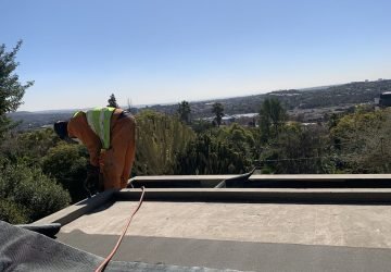 TM Waterproofing installing a torch‑on waterproofing membrane using a blow torch and roll out sheet.
