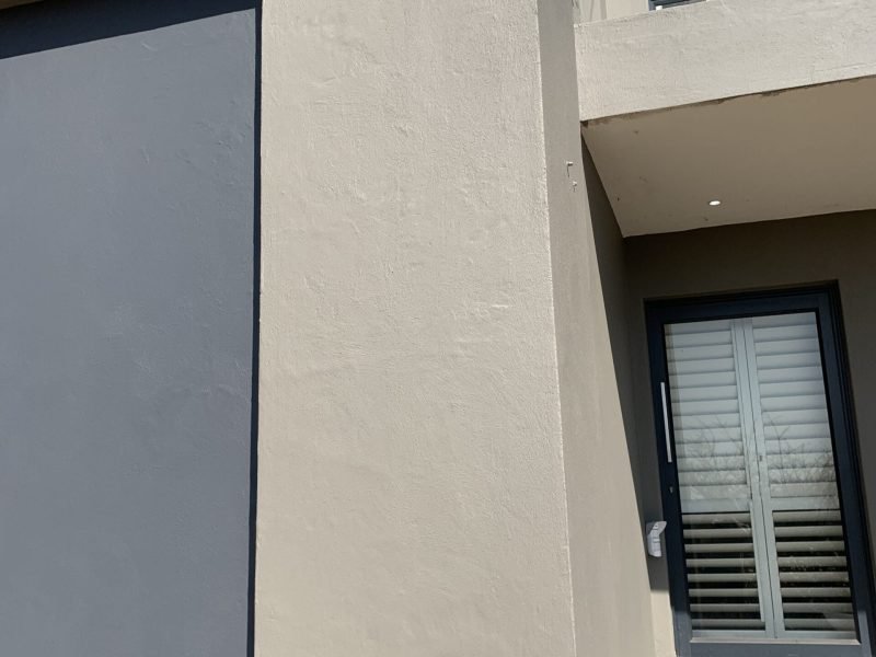 Side‑view of exterior wall including the front face, after professional waterproofing and fresh paint.