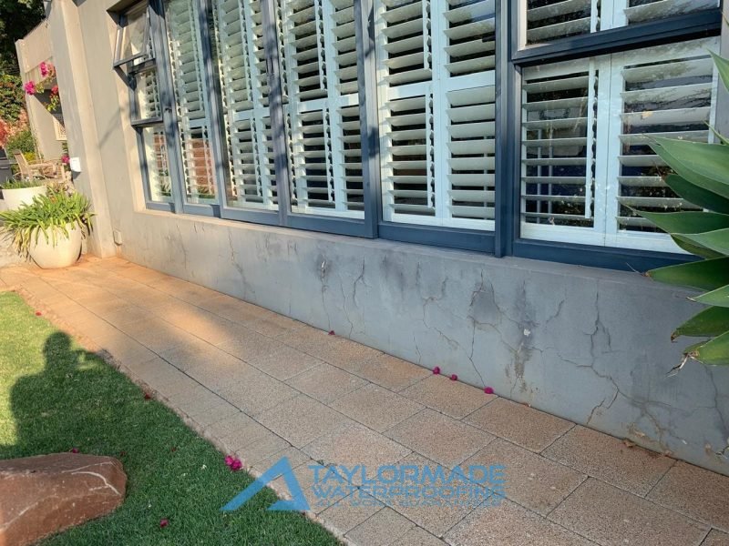 Exterior wall exhibiting visible cracks and damage prior to repair and waterproofing treatments.