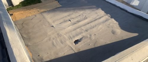 Flat roof in poor and damaged condition before board installation and Board & Torch Waterproofing by TM Waterproofing.