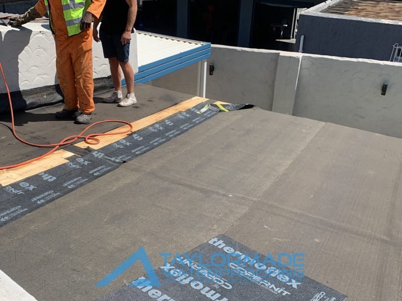 Flat roof with TM Waterproofing applying Board & Torch Waterproofing, showing continued progress of installation.