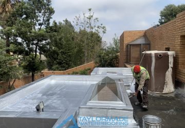 TM Waterproofing painting a flat roof after torch-on membranes application, before completion.