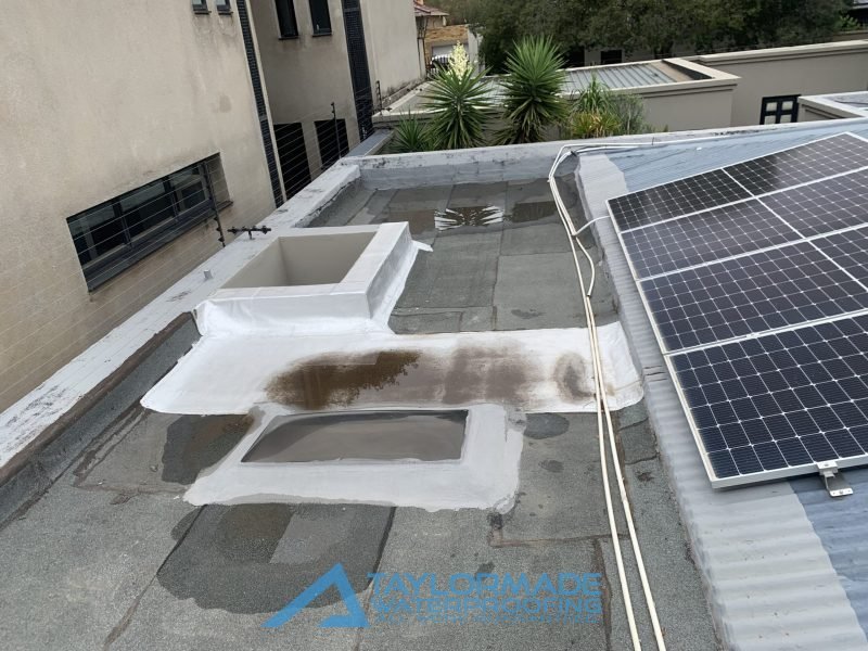 Parkhurst slab roof with torch-on membranes and protective painting applied, rainwater visible on the surface, prepared for board & torch waterproofing and torch-on membrane protection.