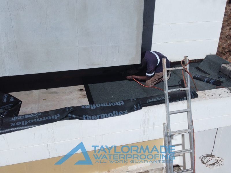 TM Waterproofing applying torch-on bitumen membrane on a balcony surface for durable waterproofing protection.