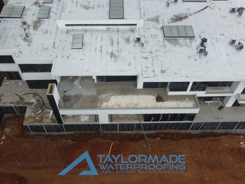 Aerial drone view of a luxury Sandton house showing roof slabs, balcony, and wall waterproofing work in progress.
