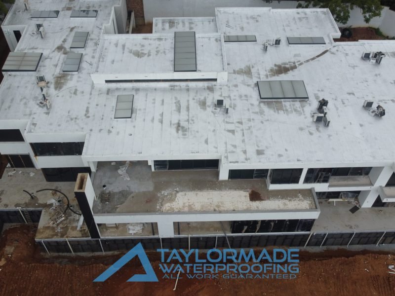 Drone aerial view of luxury Sandton home showing roof slabs and balconies undergoing waterproofing work by TaylorMade Waterproofing.